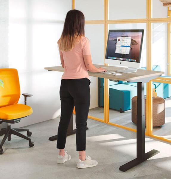 Treballadora fent servir un escriptori elevable a l'oficina